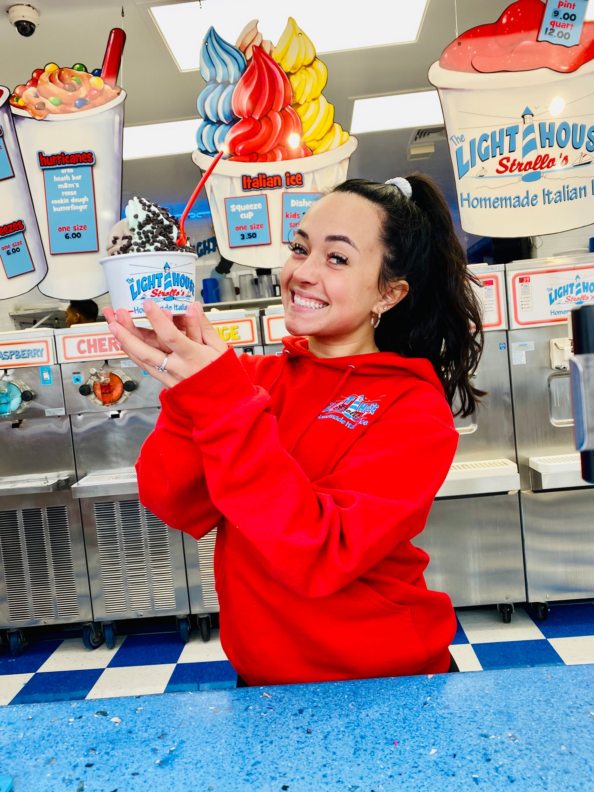 A Strollo's Lighthouse employee shows off a cup of soft serve ice cream and a big smile