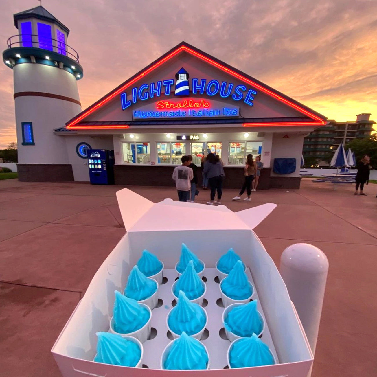 A Strollo's Lighthouse party box of blue raspberry homemade Italian Ice in front of the storefront