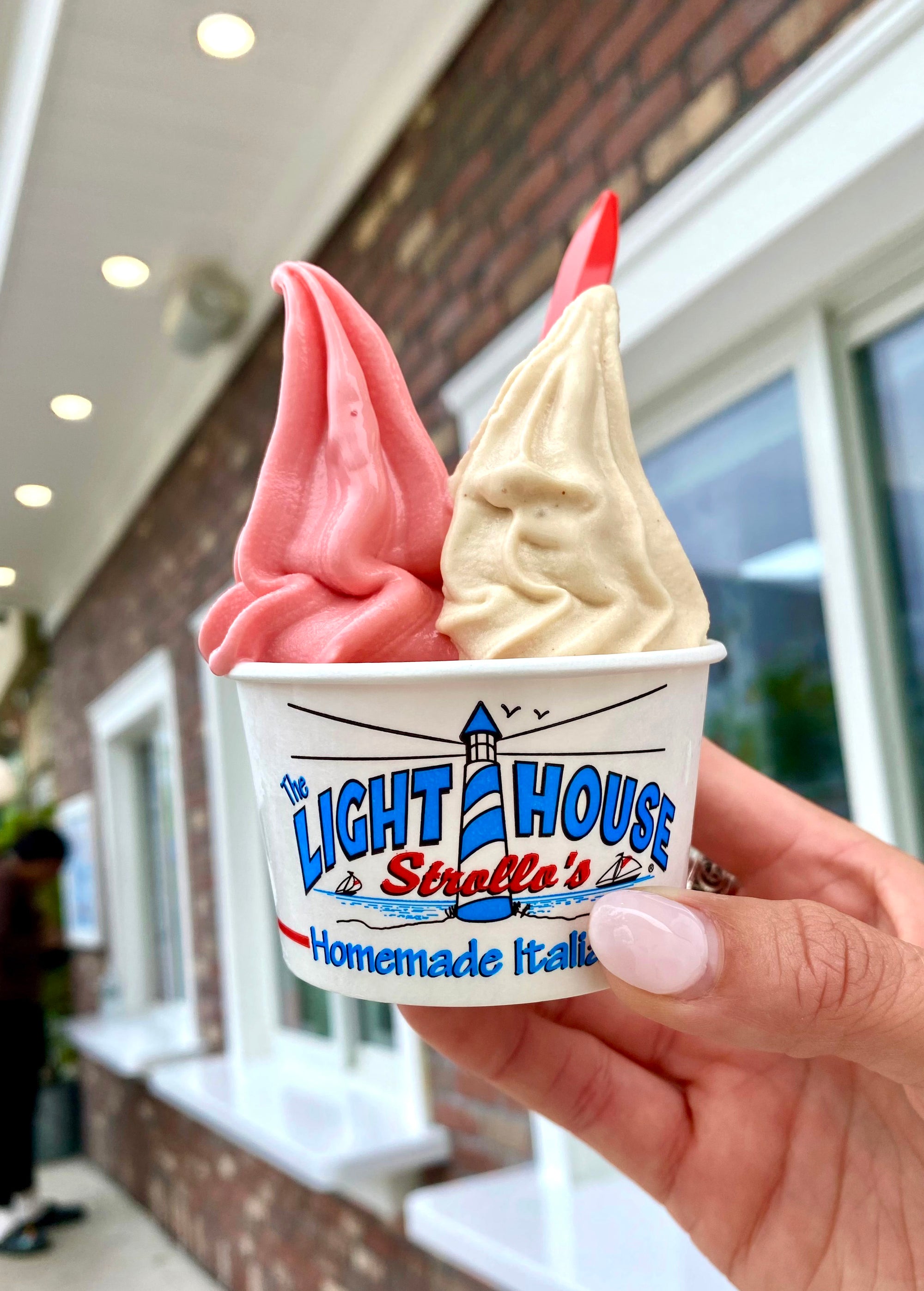 A Strollo's Lighthouse cup with two soft serve ice cream flavors, strawberry and peanut butter
