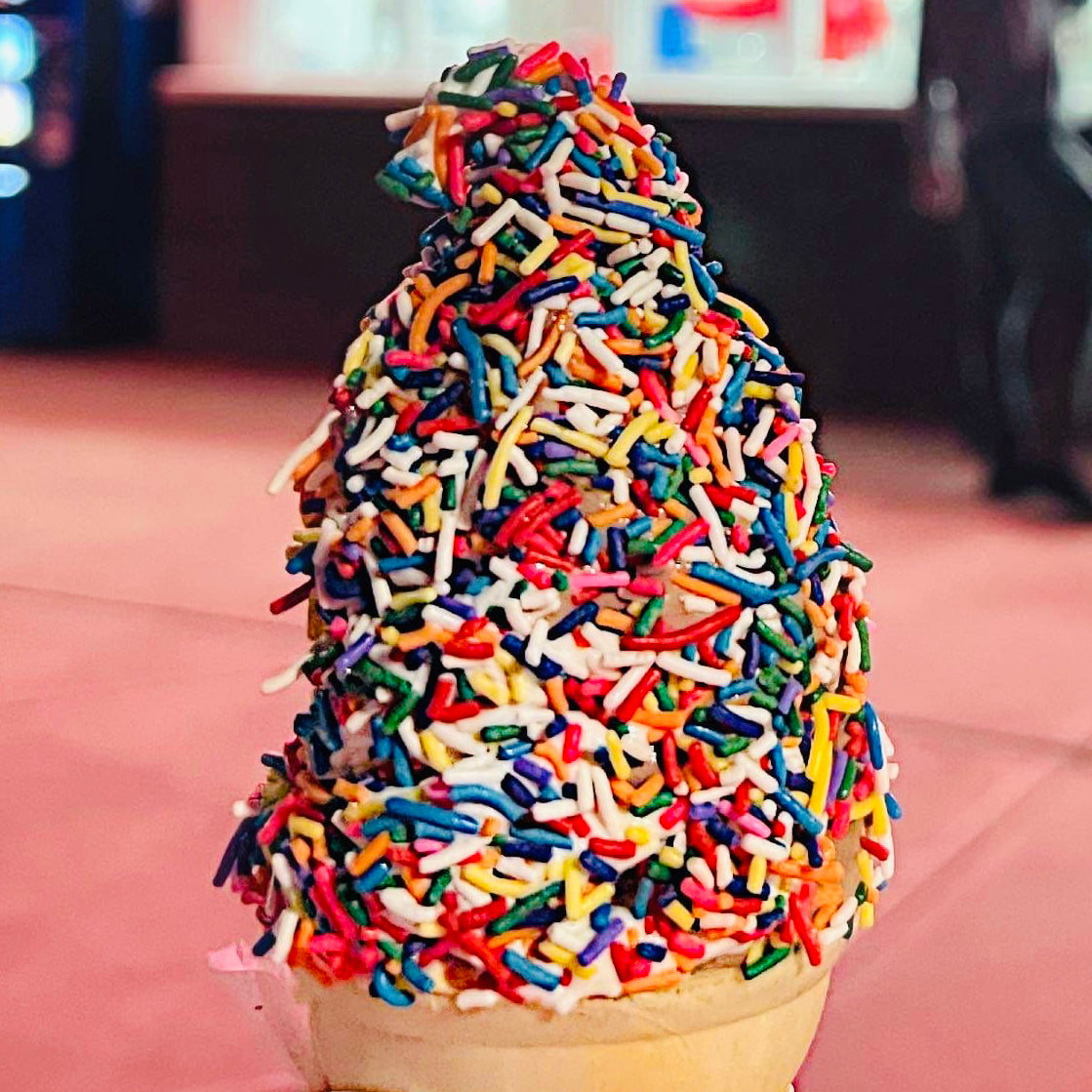 A Strollo's Lighthouse soft serve ice ream cone covered with rainbow sprinkles